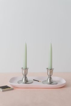 two candles sitting on top of a white plate