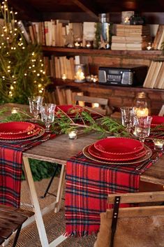 the table is set for christmas dinner with red plates and plaid cloths on it