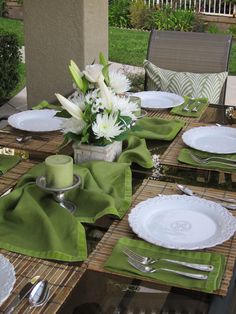 the table is set with green napkins and white flowers in a vase on it