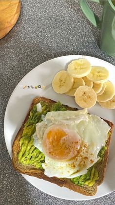 an egg and avocado toast on a plate with sliced banana's next to it