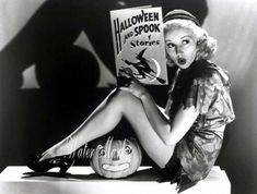 a black and white photo of a woman sitting on a pumpkin reading a halloween book