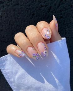 a woman's hand with some pink and purple nail polishes on her nails