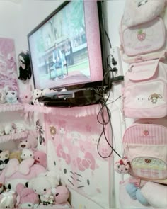 there is a television and many stuffed animals on the wall in this room with pink walls