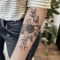 a woman's arm with a sunflower tattoo on the left side of her arm