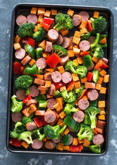 a pan filled with sausage, broccoli and peppers