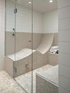 a walk in shower sitting next to a white tiled wall and counter top under a mirror