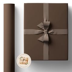 a wrapped gift box with a brown ribbon and bow on it next to a roll of wrapping paper