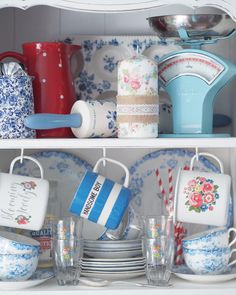 the shelves are filled with dishes, cups and other kitchen items in blue and white china