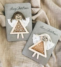 two christmas cards with angels on them sitting next to each other in front of a blanket