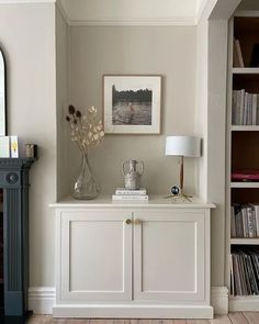 a living room with a book shelf, lamp and pictures on the wall above it