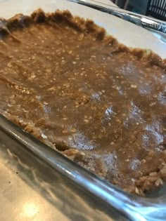 an uncooked pie sitting on top of a metal counter next to a glass pan