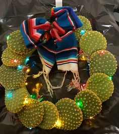 a wreath made out of cactuses with lights around it and a scarf on top