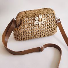 a crocheted purse with a flower on the front and brown strap around it