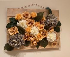 an arrangement of flowers is hanging on the wall