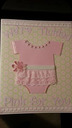 a card with a baby's pink outfit and pearls on the bottom, says we're ticketed pink for you