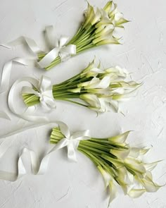 three bouquets of flowers with white ribbons