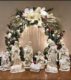 a group of statues sitting on top of a wooden table next to a christmas wreath