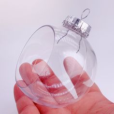 a hand is holding a clear glass ornament