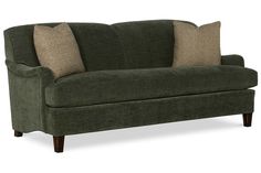 a green couch with two pillows on the arm and one pillow on the back of it