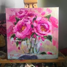 a painting of pink flowers in a vase on a easel with paintbrushes