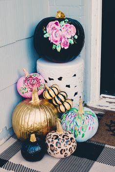 there are many decorative pumpkins sitting on the front porch door sill, all decorated in different colors and designs