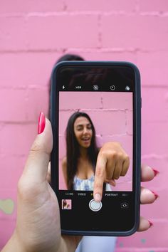 a woman is holding up her cell phone to take a selfie with the camera