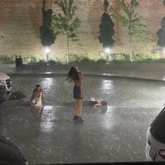 two women are standing in the middle of an empty parking lot with cars parked nearby