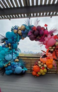 colorful balloons and palm leaves are hanging from a pergolated roof over a deck