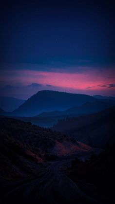 the sun is setting in the distance over some hills and valleys with trees on each side