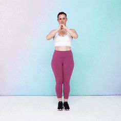 a woman standing in front of a blue and pink wall with her hands clasped to her chest