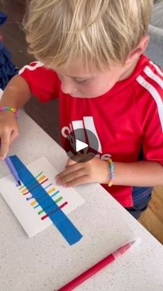 a little boy that is sitting at a table with some pencils in his hand