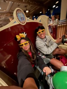 two people wearing yellow sunglasses sitting on a roller coaster