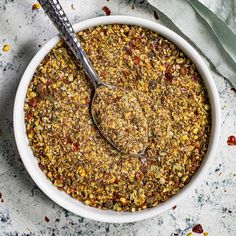 a white bowl filled with granola on top of a gray counter next to a spoon