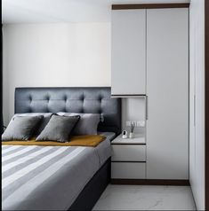 a bedroom with white walls and grey bedding is pictured in this image, there are pillows on the bed