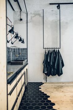 an industrial style kitchen with black and white tiles on the floor, hanging clothes from hooks