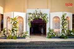 an entrance decorated with white flowers and greenery for a wedding or reception at the hotel