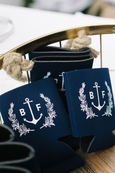 two navy blue bags with white anchors and laurels on them sitting on a table