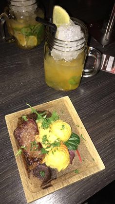 a wooden cutting board topped with meat and veggies on top of a table