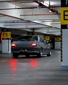 a car parked in a parking garage with red lights on the floor and yellow signs above it