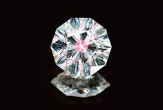 a close up of a diamond on a black background with reflection in the glass surface