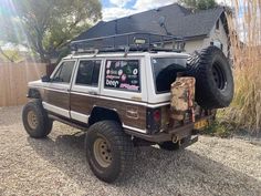 a white and brown truck with some big tires on it's flatbed in front of a house