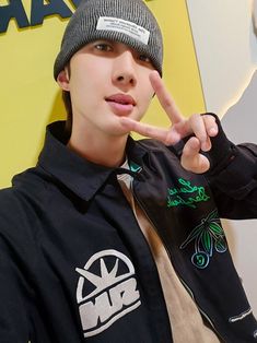 a young man making the peace sign with his hand while wearing a beanie hat