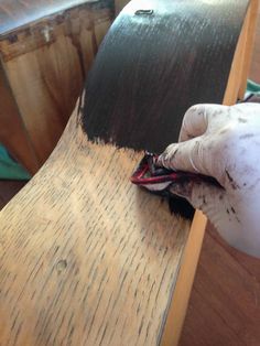 a person with white gloves is painting a wooden table