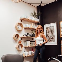 a woman standing next to a chair in a room with lots of shelves on the wall