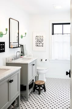 a white bathroom with black and white tile flooring, two mirrors on the wall