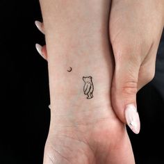 a woman's hand with a small bear and moon tattoo on her left wrist