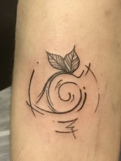 a black and white photo of a small tattoo on the leg, with a spiral design