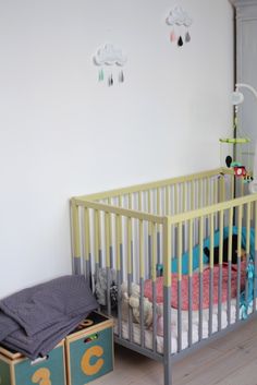 a baby crib in the corner of a room with toys and blankets on it