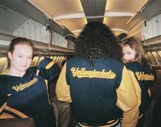 two women in yellow and black jackets on an airplane with their arms around each other