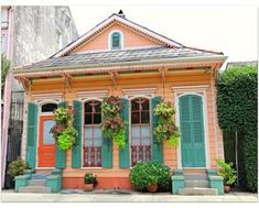 an orange house with green shutters and potted plants on the front porch is shown